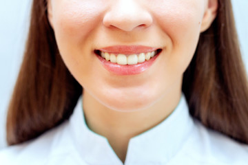 Mouth of a girl with a snow-white smile. Girl in a white coat