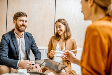 Young couple talking with a sales manager or real estate agent, offering some products with a...