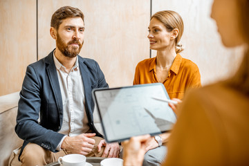 Young couple talking with a sales manager or real estate agent, offering some products with a...