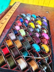 Obraz premium Colors of thread shuttles are preparing for sewing machine. This helps mend cloths.