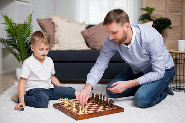 young father playing chess with his little cute son