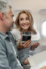 Nice smiling lady showing perfume for man in cabin