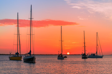 Group of sailing boats on sea at sunset