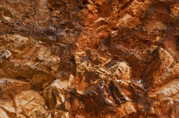 Rocky wall in orange and gold tones of the old gold mines of Rodalquilar in the province of Almeria in Spain.