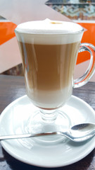 Latte coffee on a white plate. Cappuccino in glass cup for Breakfast.