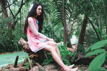 Young beautiful asian woman in pink dress sitting in garden