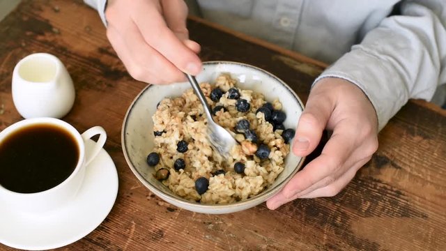 Person eating oatmeal porridge with blueberries for a healthy breakfast