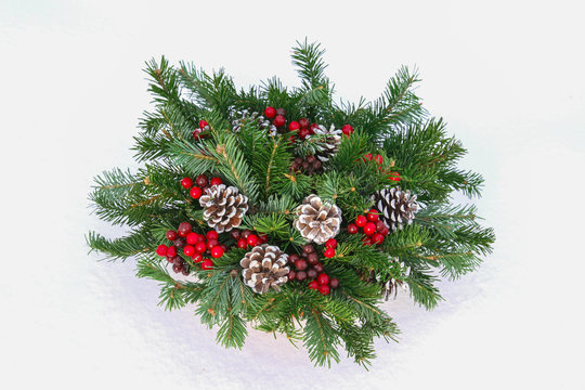 Closeup New Year wicker basket with snow covered spruce evergreen branches, cones and red berries. - Powered by Adobe