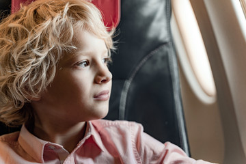 Fototapeta na wymiar Little boy is sitting near window in plane