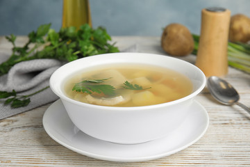 Delicious fish soup in bowl on white wooden table