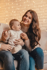 Ьom with little baby sitting on bed in decorated interior.