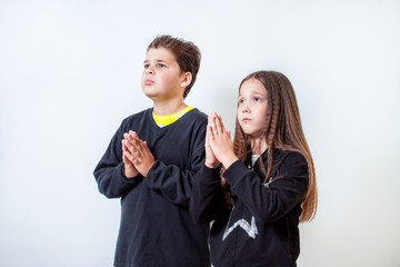 A little girl and a boy pray. Children ask for something