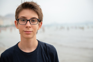 Handsome young boy at beach in Alicante. Beautiful calm smiling teen boy at Mediterranean sea coast in Spain. Travel, summer vacation, tourism, teenage lifestyle.