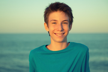 Handsome young boy at beach. Beautiful calm smiling teen boy at Mediterranean sea coast. Travel, summer vacation, tourism, teenage lifestyle.
