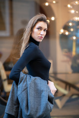 Young caucasian fashionable woman dressed in black clothesposing outdoor, Christmas Eve. Beautiful caucasian girl in Milan, Italy. Street fashion, winter holidays