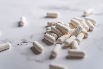 painkillers and drug abuse concept with close up on a bottle of prescription drugs and pill capsules falling out of it on a white marble table
