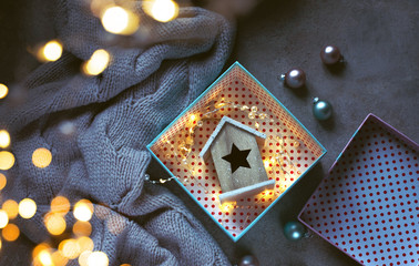 Wooden toy house with an asterisk in a gift box. Christmas background. The atmosphere of magic.