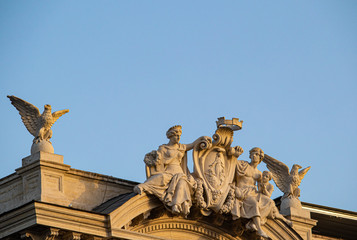 Obraz premium The statues of two eagles and a woman and a boy with a child on the top of a palace