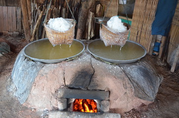 Making of salt (Sin-tao salt) at ancient salt pond in Bo Kluea district ,Nan Province,Thailand.White salt in the basket over the water that came from pond and heated by firewood.