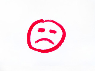 Smiley red imitating a bad mood. Smiley face painted with paints and brush on a sheet of paper. Sad smiley face on white background.