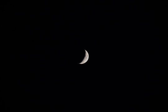 Crescent moon in the center of the dark sky.