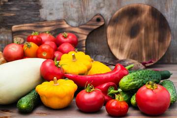 Fresh vegetables - squash, cucumbers, tomatoes, zucchini, peppers on a wooden table