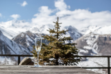 Christmas spruce tree and glass of champagne on the bacground of mountain landscape in rooms terrace in Kazbegi, Georgia