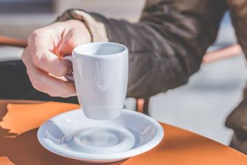 mujer irreconocible sujetando taza de café en terraza de cafetería