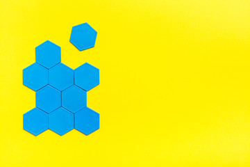 Blue hexagons form a beehive on a yellow background. One hexagon is separated from the figure. The...