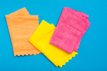 Multicolored folded microfiber rags on a blue background. Cleaning equipment concept