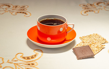 Morning home tea time. Orange cup of tea and sunflower seed cookies and chocolate bar on white tablecloth. Hot drink with steam in cup. tea time concept with bright dishes and tasty cookies.
