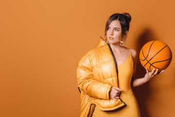 Fashionable young woman with ball on color background