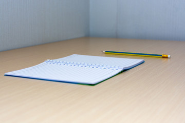 A pencil and a note book on desk.