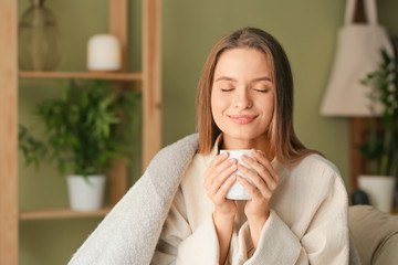 Young woman with cup of hot tea resting at home