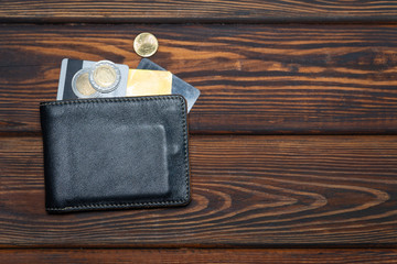 Leather wallet, with Euro coins and credit or debit cards, on a dark wooden background