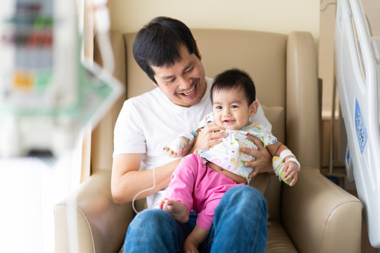 Asian father is playing and holding his baby to relax with love while the child admit as inpatient in the hospital, concept of parent take care to their sickness child in family lifestyle.