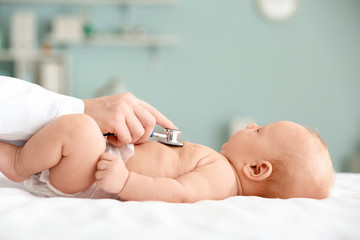 Pediatrician examining cute baby in clinic - obrazy, fototapety, plakaty