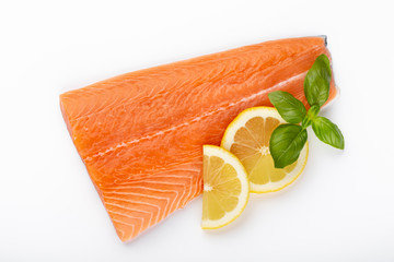 Fresh raw salmon fillets with herbs and lemon isolated on white background.