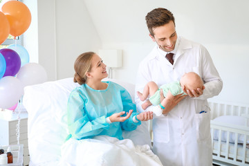 Obraz premium Young woman with newborn baby and gynecologist in maternity hospital