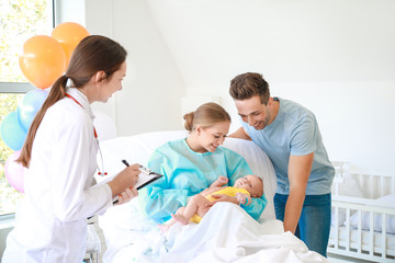 Young family with newborn baby and gynecologist in maternity hospital