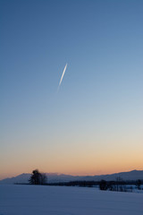 冬の夕暮れの空と飛行機雲
