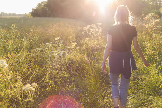 Young woman walking in the field at sunset