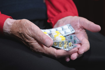Closeup of a tablet on the hands of an old woman. The concept of choosing medication in old age