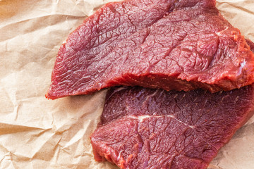 Two large raw beef steaks lie on food paper