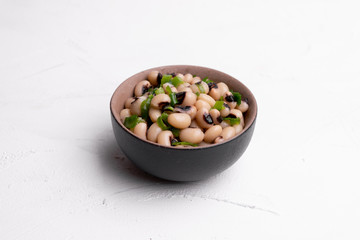 Cooked Fradinho beans in a black clay pot, isolated on a white background.
