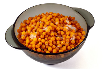 Frozen fruits of sea buckthorn in a black transparent plate on a white background