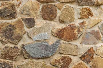 Background in the form of a stone wall of large gray and brown stones, side view