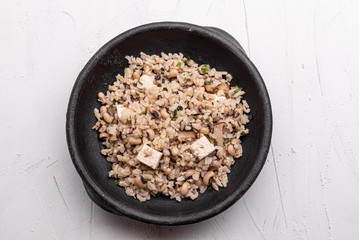 Baião de Dois - Brazilian Traditional Food - made with sausage, curd cheese, dried beef and rice in a black clay pot, on white background. Typical dish of Northeast Brazil.