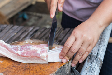 Vendor used a knife slice the pork into pieces for sale.
