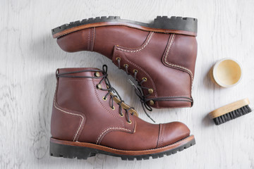 ฺBrown leather shoes with vintage camera on a wooden floor.Brown vintage leather boots aligned selective focus.Men leather shoes 
